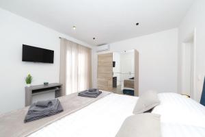 a white bedroom with a bed and a television at Villa Bonavita in Sukošan +51 photos