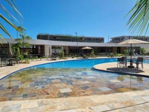 a swimming pool with tables and chairs and a building at Mana Experience Muro Alto in Porto De Galinhas