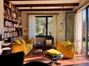 un soggiorno con mobili gialli e librerie di Casa d'epoca con giardino 5 min da Locarno a Minusio