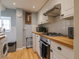 a kitchen with white cabinets and a stove top oven at Old Ropemakers Cottage in Bridport