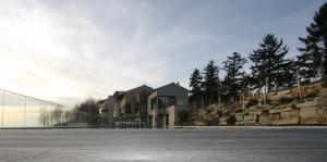 a building in a parking lot next to a fence at Qb Apartments in Montelupo Albese