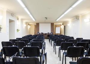 ein leeres Zimmer mit Stühlen und einem weißen Bildschirm in der Unterkunft Hotel Hambros - Il Parco in Villa Banchieri in Lucca