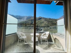 a balcony with chairs and a view of a mountain at Hotel Virasat-E-Bushahr in Rāmpur