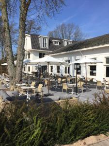 um pátio com cadeiras, mesas e guarda-sóis em frente a um edifício em Fletcher Hotel Het Veluwse Bos em Beekbergen