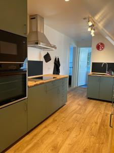 a kitchen with stainless steel appliances and wooden floors at Søndervang, lejlighed 1sal in Svinninge