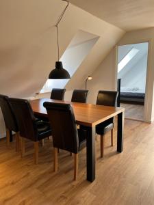 a dining room with a wooden table and black chairs at Søndervang, lejlighed 1sal in Svinninge