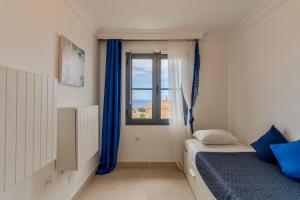 a bedroom with a bed and a window with blue curtains at Charming semi- detached villa in Mirador del Duque in Adeje