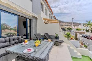 a patio with a wooden table and chairs on a balcony at Charming semi- detached villa in Mirador del Duque in Adeje
