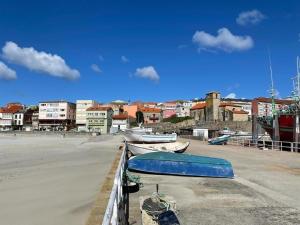 zwei Boote liegen in einem Hafen mit Gebäuden in der Unterkunft Grupo Gontad Apartamento Rompeolas in Laxe