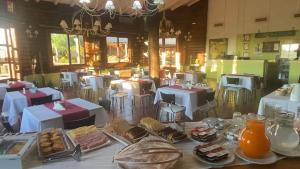 a restaurant with white tables and chairs with food at HOTEL Bambys Lodge in Concordia