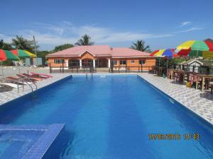 Jamaica Inn Guest House في Botianaw: مسبح كبير مع مظلات ومنزل