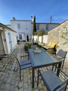 a patio with a table and chairs and a building at Maison 4 pièces 6 couchages Saint Denis d'Oléron SDO000-382 in Saint-Denis-dʼOléron