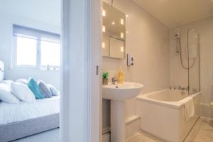 a bathroom with a sink and a bath tub next to a bed at Spacious 2-Bed City Home Free Parking & Stadiums in Glasgow +22 photos