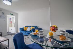 a living room with a glass table and blue chairs at Spacious 2-Bed City Home Free Parking & Stadiums in Glasgow