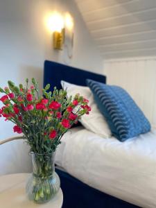 a vase with red flowers on a table next to a bed at Apartamenty Plac Moniuszki 11 City Center in Kielce