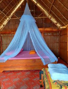 a bed in a straw hut with a mosquito net at Rosye homestay raja ampat in Fam