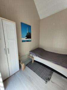 a small bedroom with a bed and a lighthouse at Domki Eridan nad morzem in Wisełka