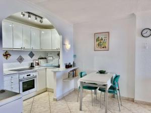 a kitchen with white cabinets and a table and chairs at Beach Apartment Arguineguin in Arguineguín