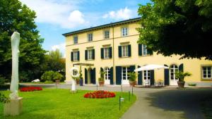 ein gelbes Gebäude mit einer Statue davor. in der Unterkunft Hotel Hambros - Il Parco in Villa Banchieri in Lucca