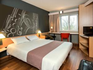 a hotel room with a large bed and a desk at ibis Dinant Centre in Dinant