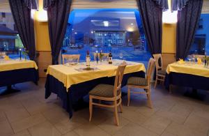 a dining room with two tables with yellow tablecloths at Hotel Bernina in Tirano