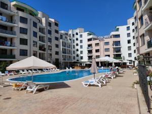 a swimming pool with lounge chairs and umbrellas in front of buildings at Avalon Lux in Sunny Beach