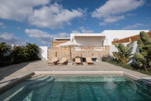 a pool with chairs and an umbrella next to a house at Petradia Villas in Naxos Chora