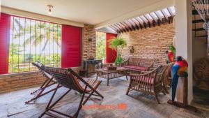 a living room with chairs and a table and windows at Casa charmosa a beira-mar em Paripueira - AL in Paripueira