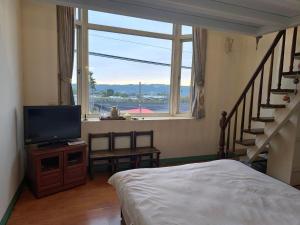 a bedroom with a bed and a television and a window at 馨舍民宿 in Xinshe