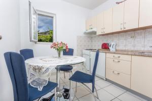 a kitchen with a table with blue chairs and a vase of flowers at Apartman Ana in Hvar