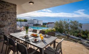- une table et des chaises sur une terrasse avec piscine dans l'établissement Villa Mattina, à Dolac