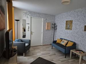 ein Wohnzimmer mit 2 blauen Sofas und einem TV in der Unterkunft 1 rue des romains studio meublé clauss in Niederbronn-les-Bains
