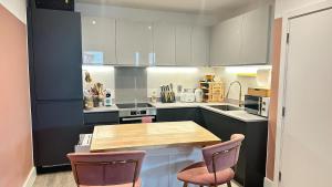 a kitchen with a wooden table and two chairs at The Pink Perfect Place in Abbey Wood
