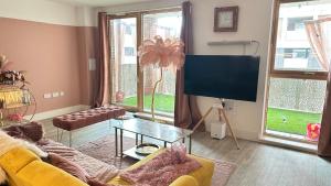 a living room with a yellow couch and a flat screen tv at The Pink Perfect Place in Abbey Wood +4 photos
