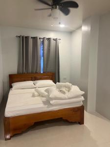 um quarto com uma cama com lençóis brancos e uma ventoinha de tecto em RUBY Suites em Baguio