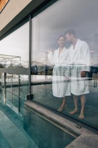a man and a woman standing in a window at Hotel Avelina in Avelengo