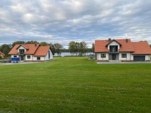 two houses with red roofs on a green field at Osada Limajno Dom Żurawia in Cerkiewnik