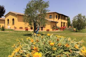 una gran casa amarilla con un patio con flores en Podere Tre Cipressi Country Resort, en Campiglia Marittima