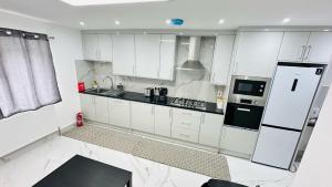 a kitchen with white cabinets and black appliances at 93 New Road in Harmondsworth