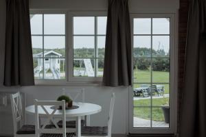 a white table and chairs in a room with windows at Atostogų pieva in Žibininkai