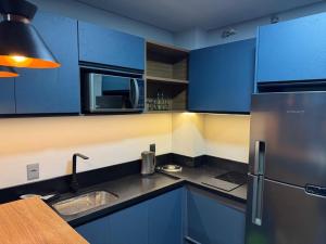 a kitchen with blue cabinets and a stainless steel refrigerator at Loft in Xangri-lá
