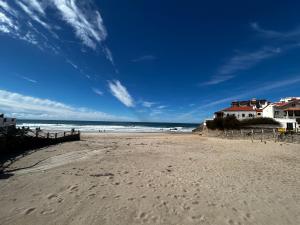 a beach with footprints in the sand and houses at Corn House, São Pedro de Moel Sea View in Marinha Grande