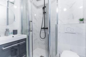 biała łazienka z prysznicem i umywalką w obiekcie Home Suite Home Grands Boulevards 41 w Paryżu