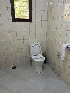 a bathroom with a toilet with the seat up at Kivuli Lodge in Moshi