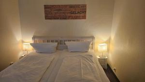 a bedroom with a bed with two pillows and two lamps at Strandhotel - Budget in Hohwacht +4 photos