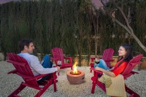 a man and a woman sitting in chairs around a fire at Villa Elia, Cinema, Gym, KidsRoom, Pool & BBQ in La Eliana