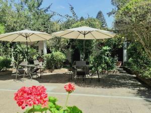 a patio with tables and umbrellas and flowers at La Chacra de Joel Hotel in Huehuetenango