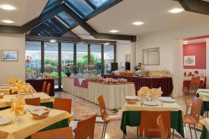 a dining room with tables and chairs and windows at Hotel Europeo in Sottomarina