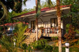 ein Haus mit einer umlaufenden Veranda mit Palmen in der Unterkunft Koh Kood Garden House in Ban Lak Uan