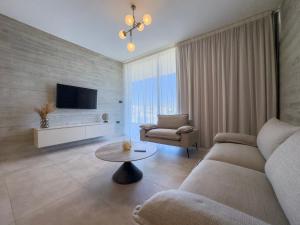 a living room with a couch and a table at Malberry Park 301 - Modern 2bedroom Apt with Shared Heated Pool, Sauna, Gym, Jacuzzi in Paphos City